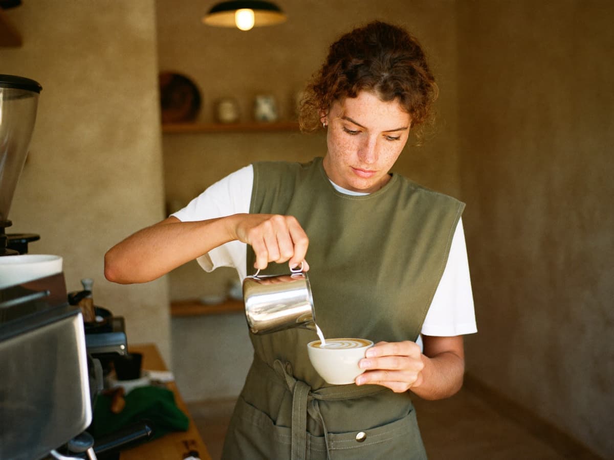 Barista prepara un café con arte latte en una cafetería de especialidad