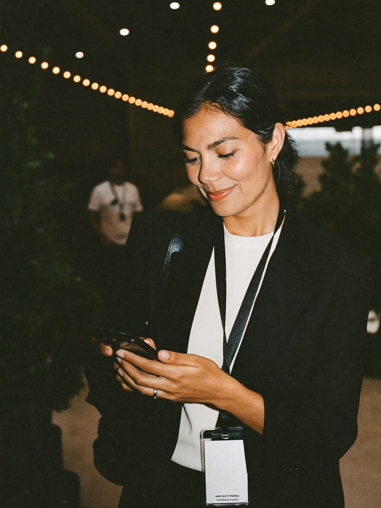Organizadora de una expo sonríe al revisar su teléfono en la entrada del evento
